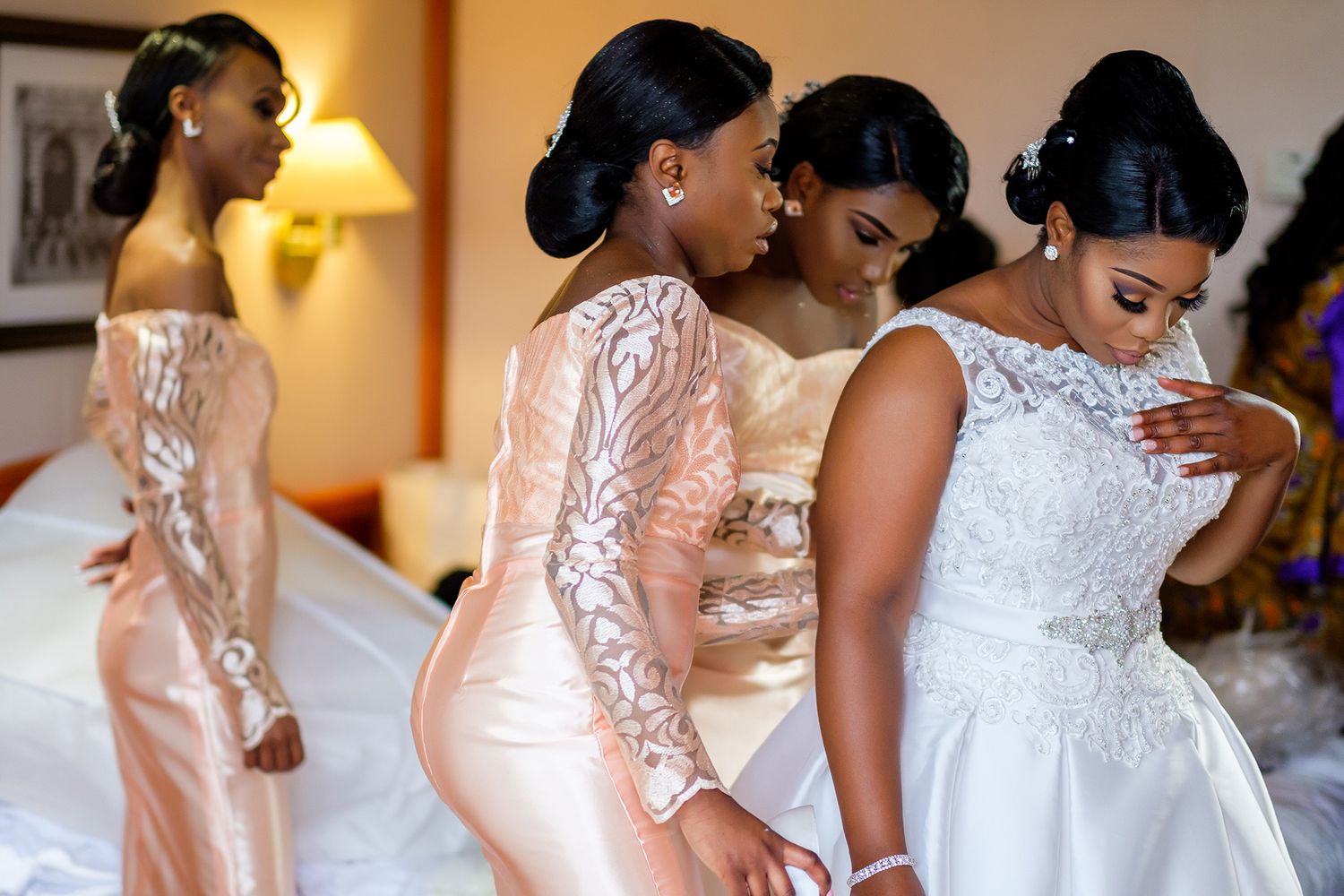 Bridesmaids in blush pink dresses help prepare for a wedding celebration.
