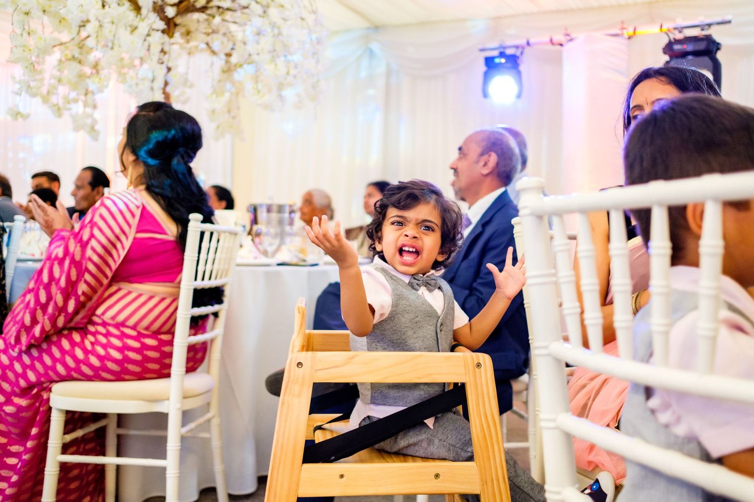 Wedding reception venue with elegant white decor and chandelier lighting.