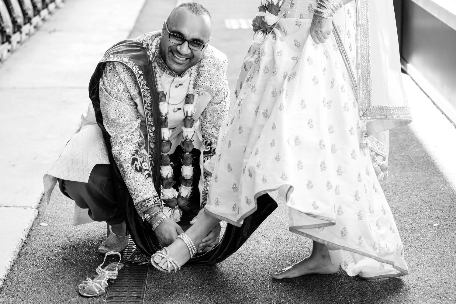 Wedding couple and guests pose for creative black and white railway track photos during celebration.