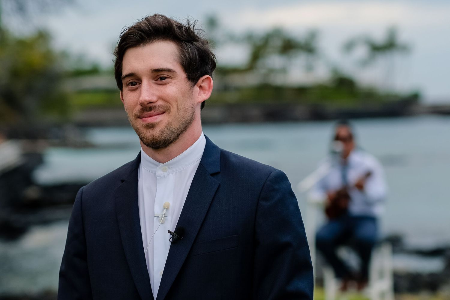 Wedding party members in formal attire gathered at an oceanside location.