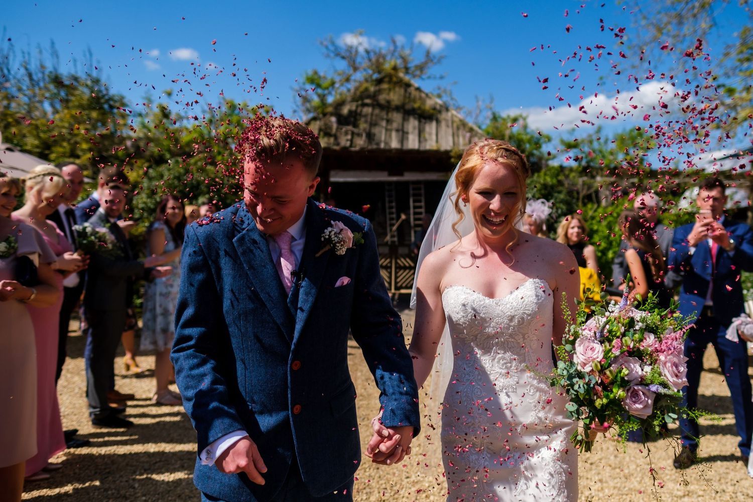 Wedding celebration with confetti toss under bright blue summer sky.