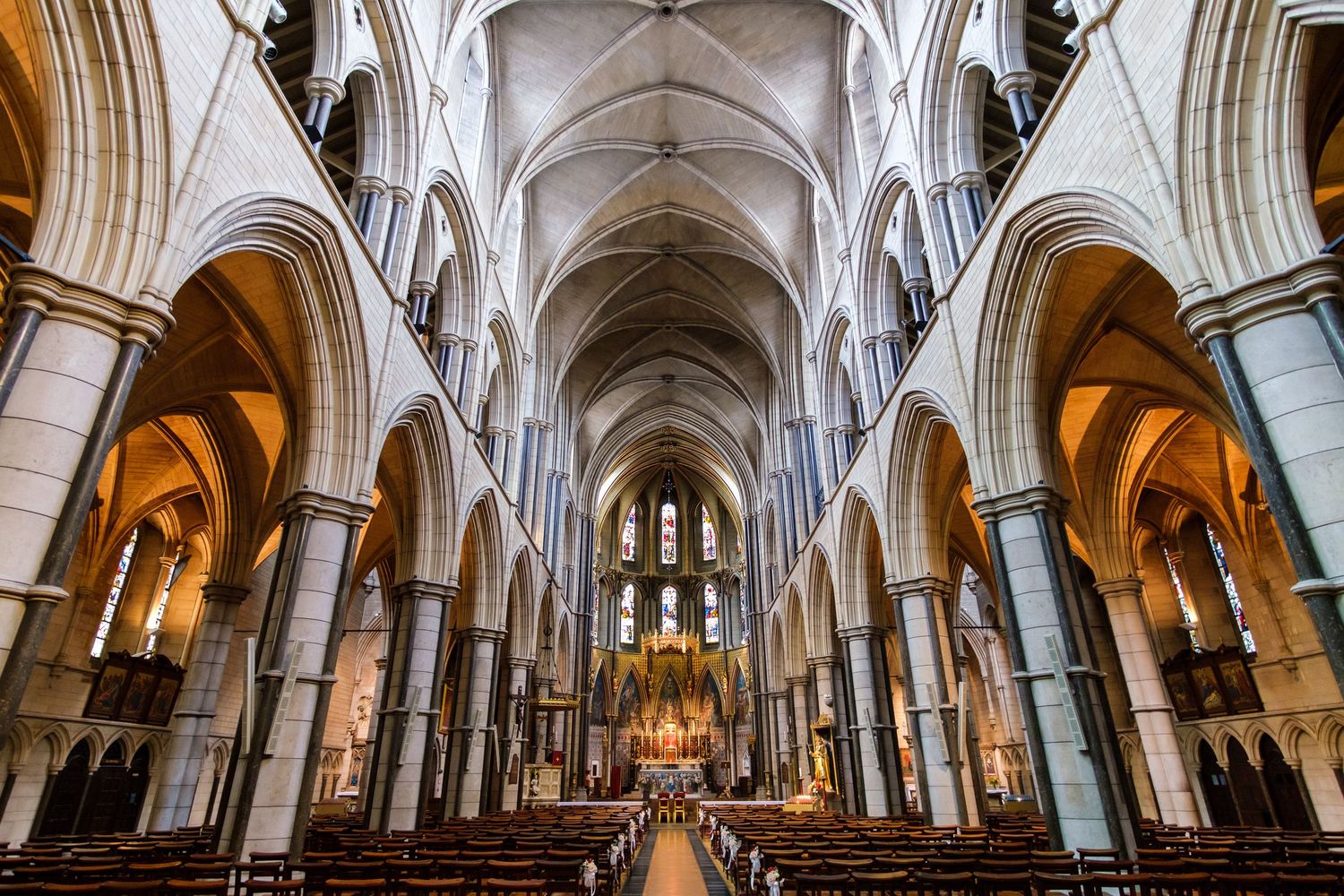 Stunning cathedral interior with soaring Gothic arches and ornate architectural details illuminated by warm lighting.