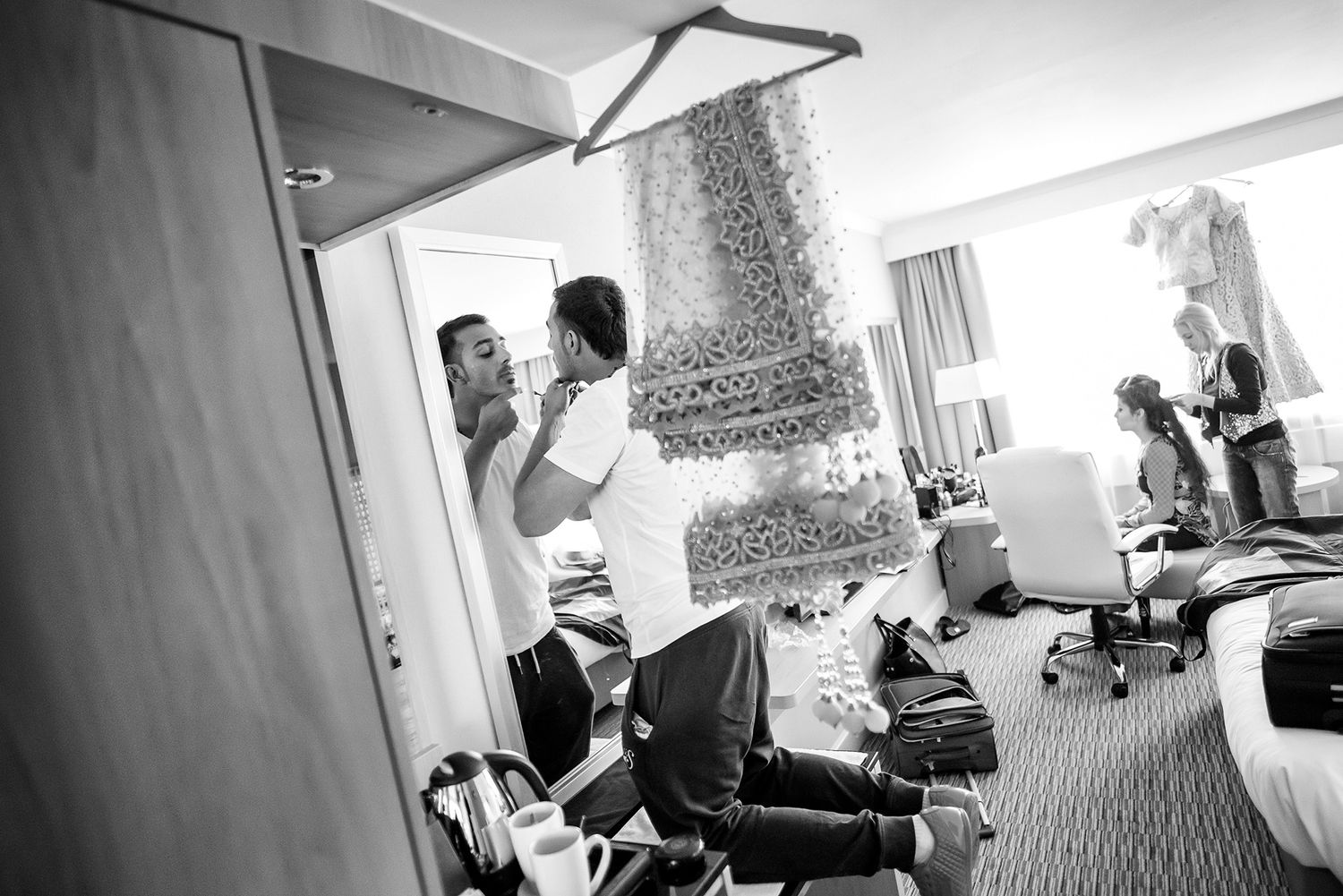 Black and white wedding preparation scene in a hotel room.