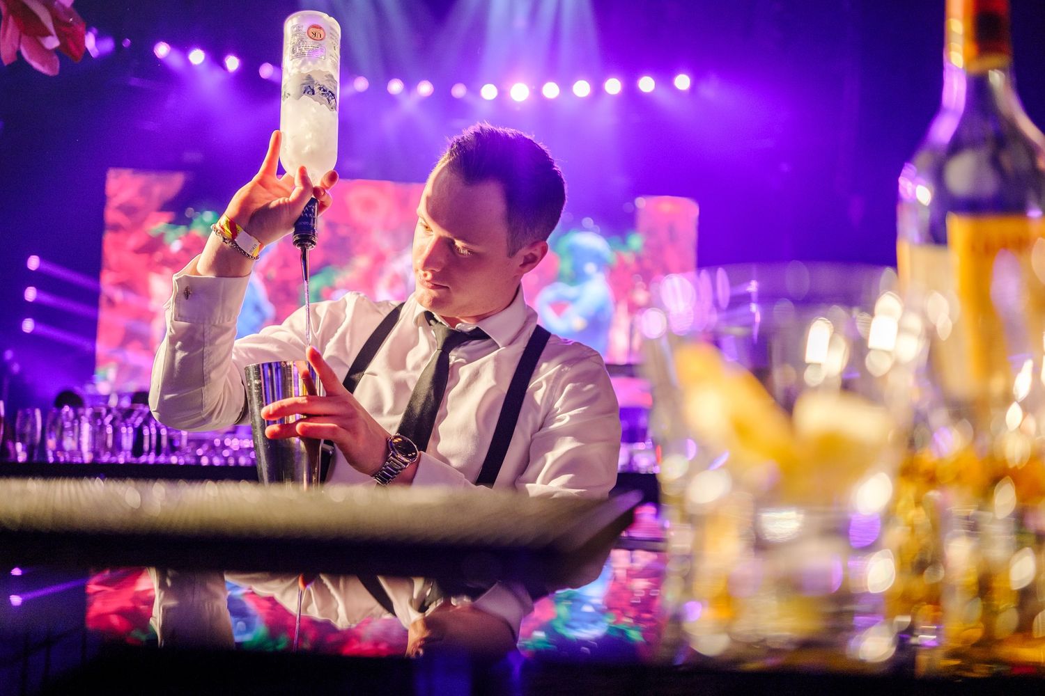 Colorful purple and blue stage lighting illuminates performers at a nightclub or concert venue.