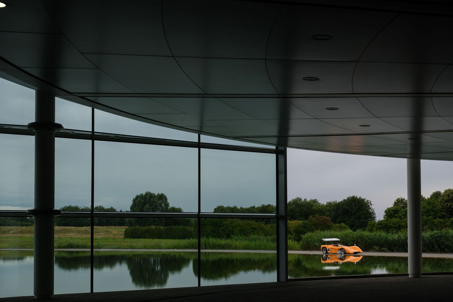 Modern building interior with curved window overlooking serene lake landscape.