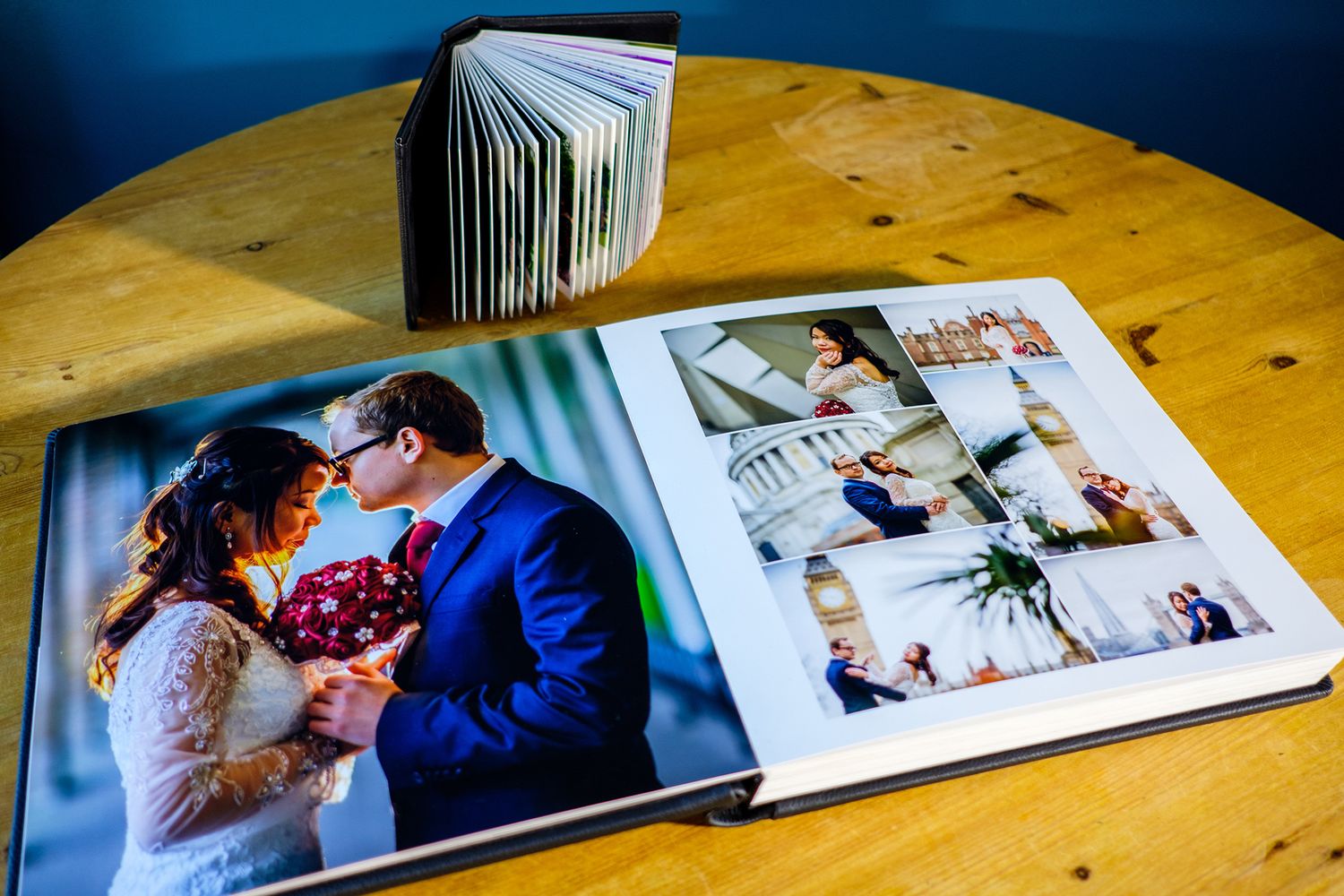 Open wedding photo album showing multiple event photographs laid out on wooden table.