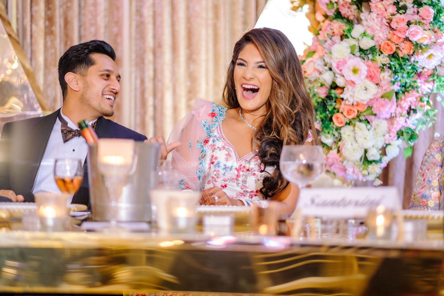 Wedding reception table setting with pink floral arrangements and decorative elements.