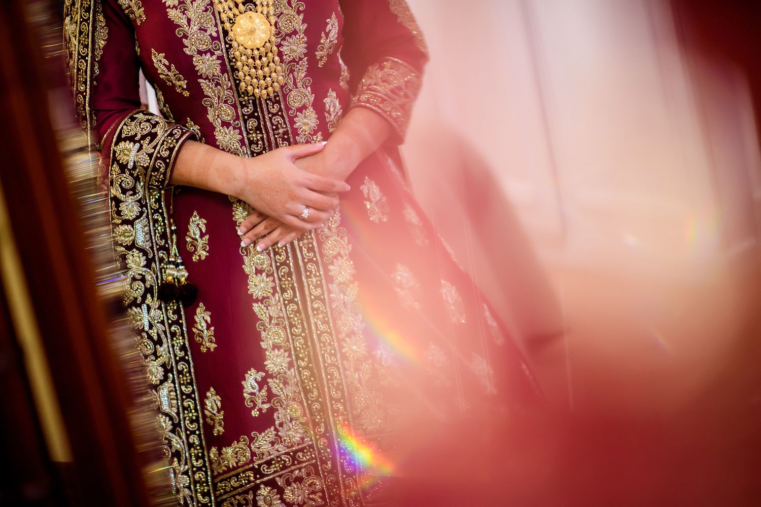 Close-up detail of intricate gold embroidery on a deep red traditional wedding dress.