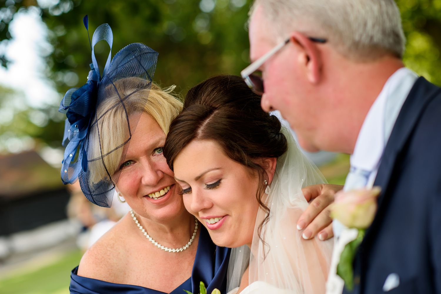 Tender moment shared between wedding party members on a sunny outdoor day.