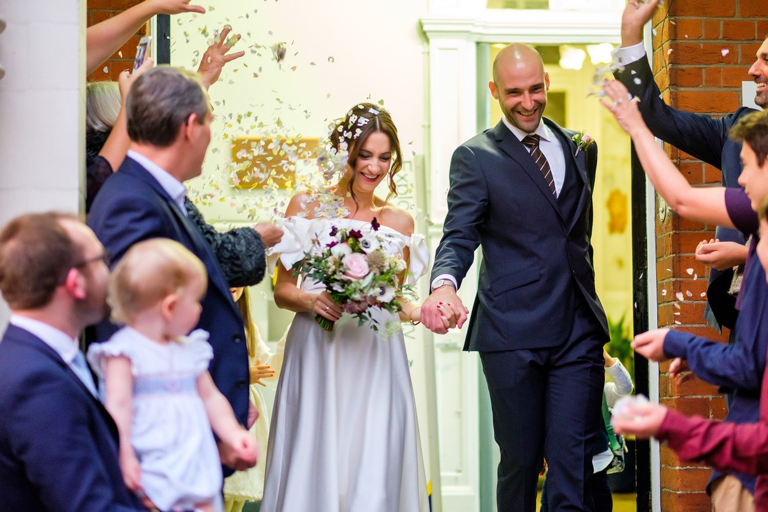 Sunlit wedding celebration with guests gathering in a traditional venue setting.