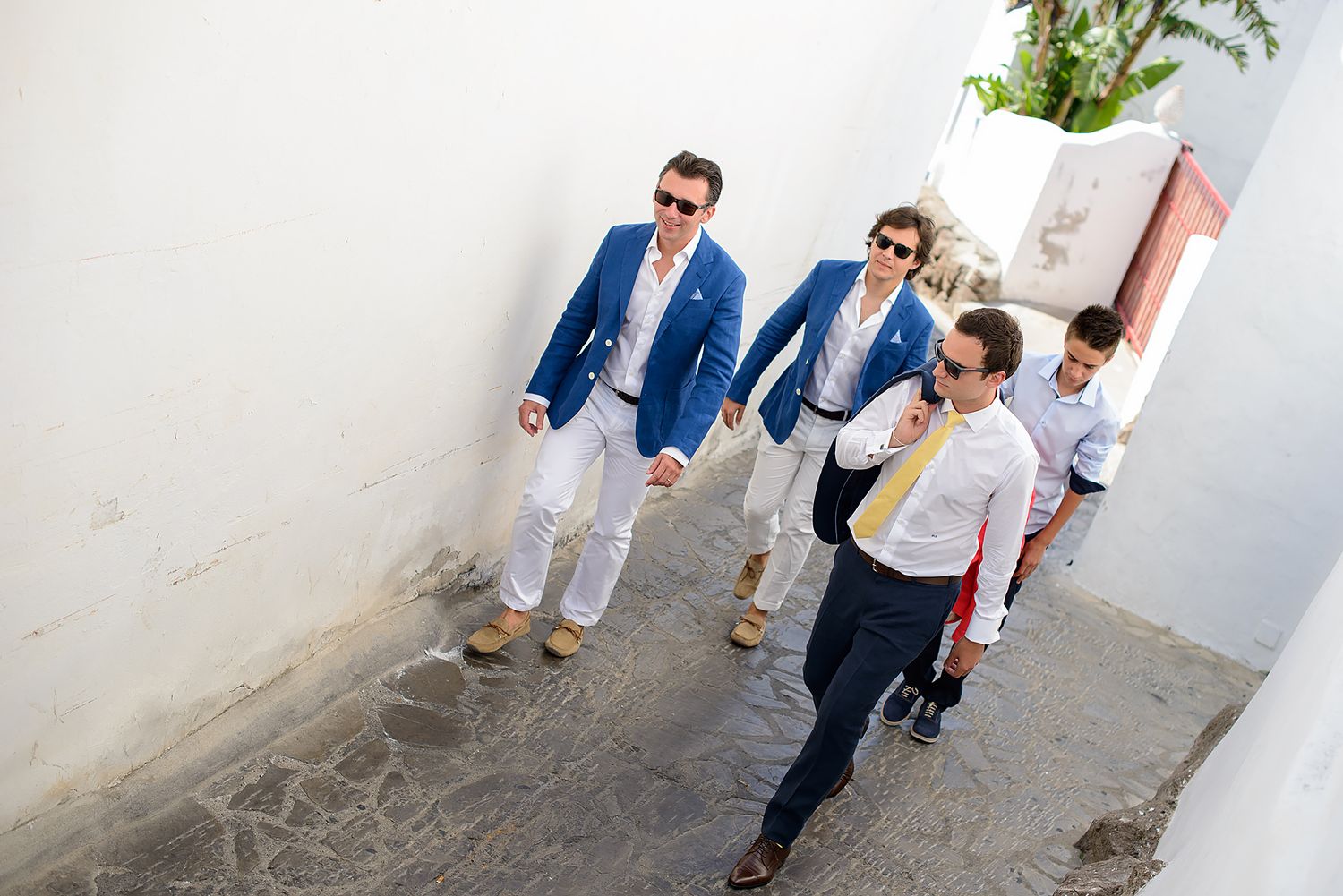 Wedding party walking through white Mediterranean-style courtyard.
