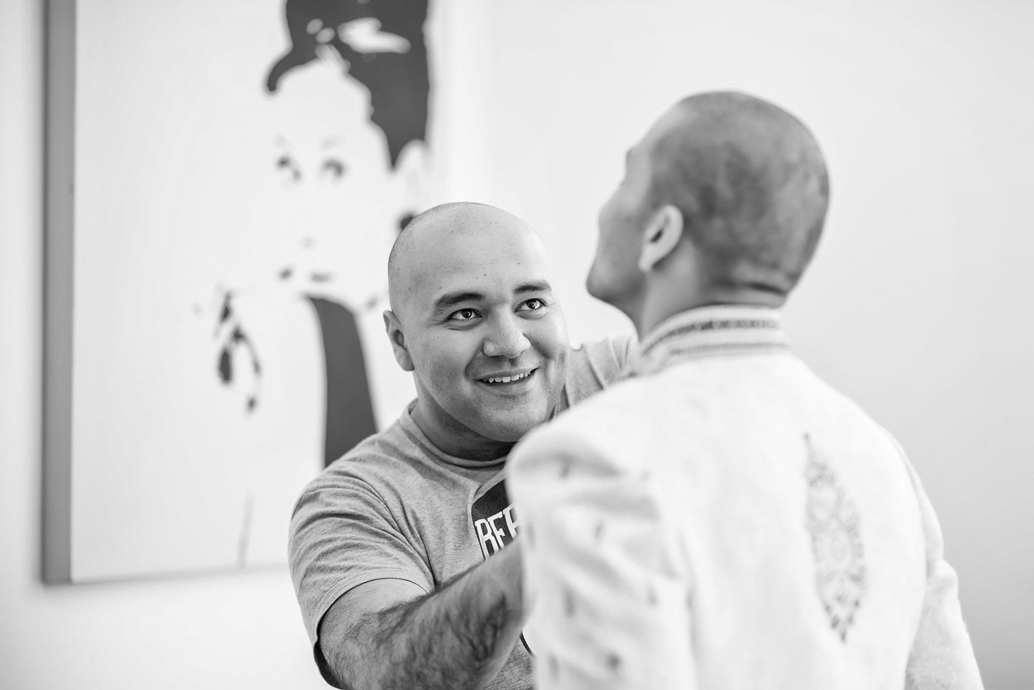 Two people share a candid moment in front of black and white wall art.