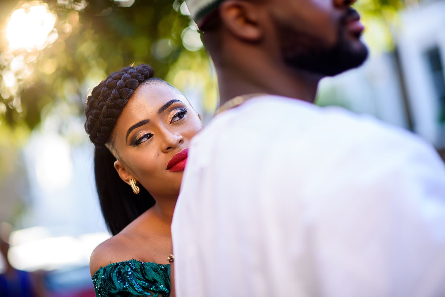Golden sunlight filters through trees as a couple shares an intimate moment outdoors.