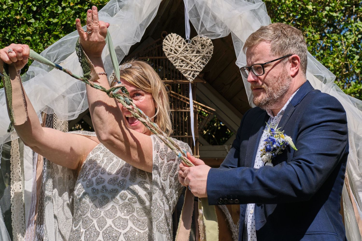 Wedding party celebrates outdoors with yellow flowers blooming in the background.