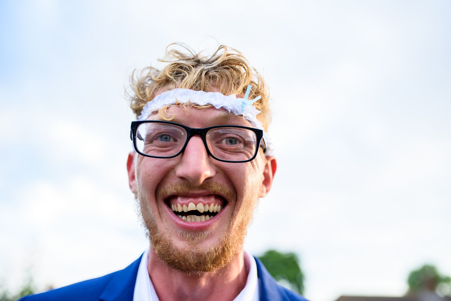 Wedding party member in blue suit celebrates enthusiastically outdoors.