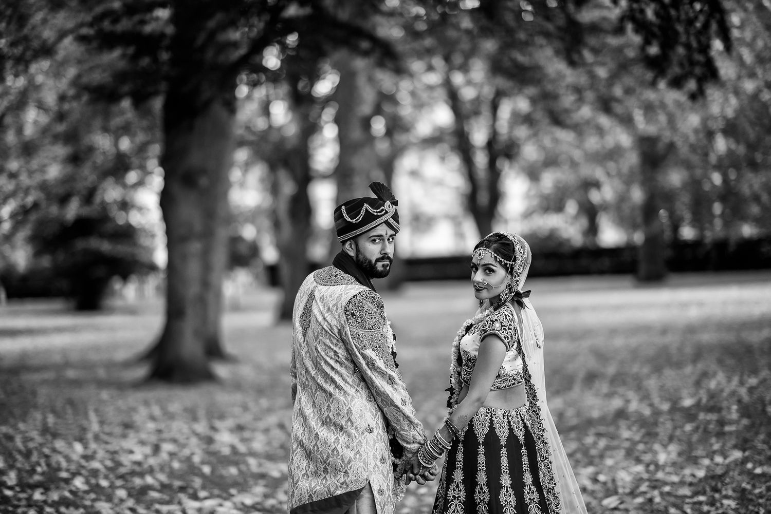 Black and white photo of a couple walking together on a tree-lined path.