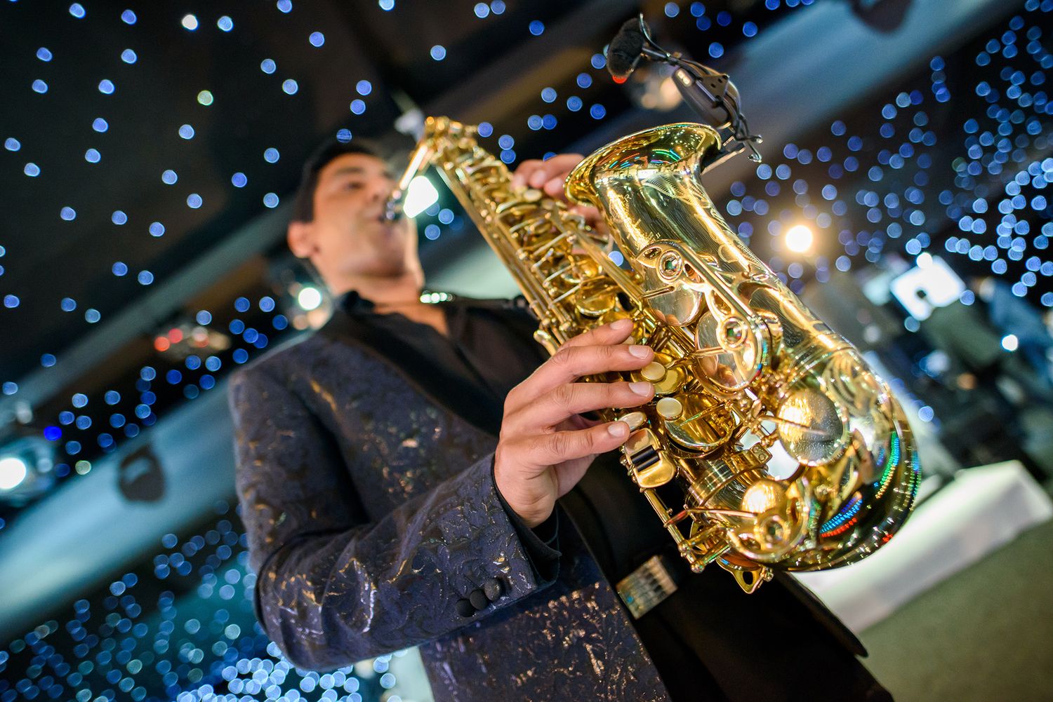 Musicians playing saxophones under twinkling blue lights at formal event.