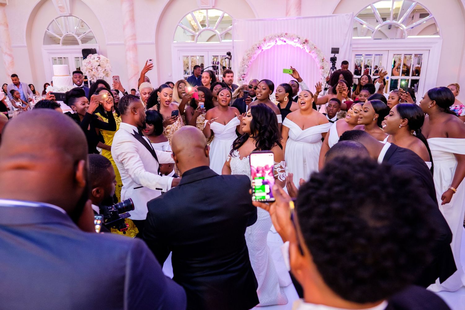 Panoramic view of a wedding reception ballroom filled with dancing guests and elegant decor.