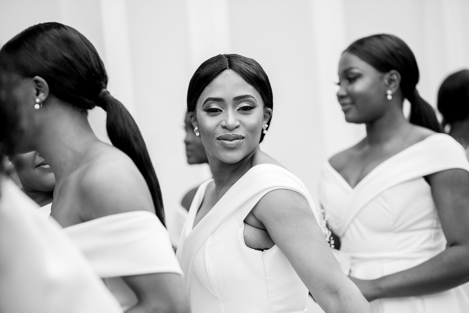 Wedding party members wearing elegant white dresses in a bright indoor setting.