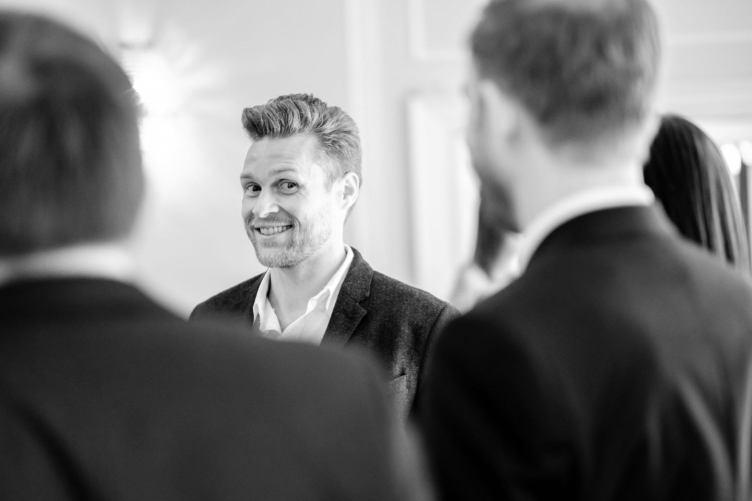 Black and white candid shots of wedding guests sharing joyful moments.