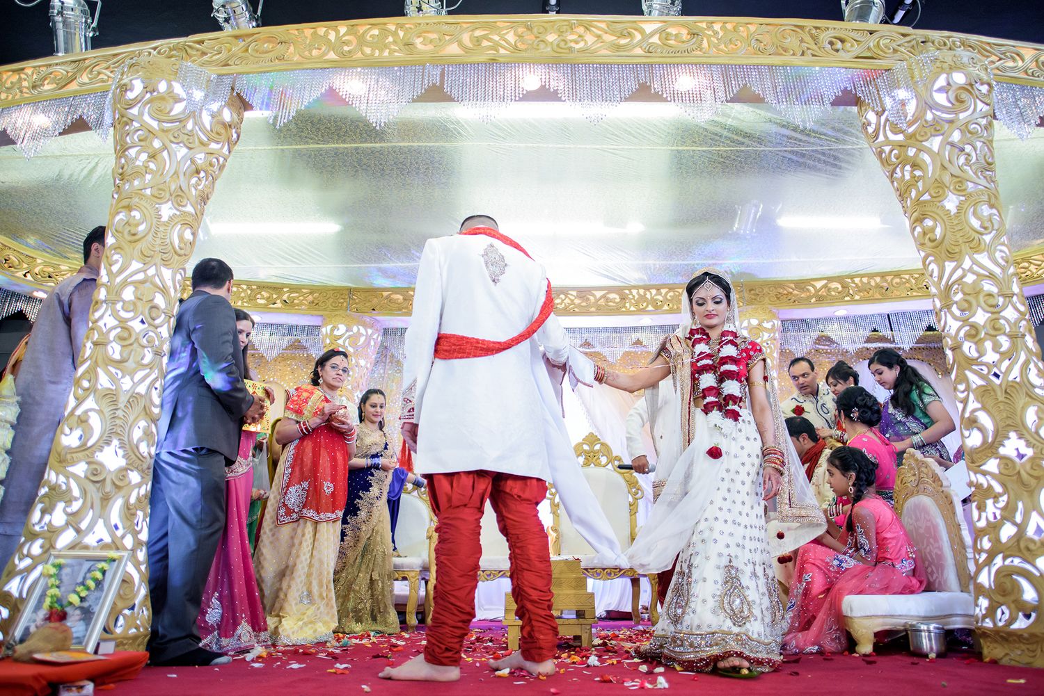 Traditional Indian wedding ceremony with gold decor and guests celebrating in formal attire.