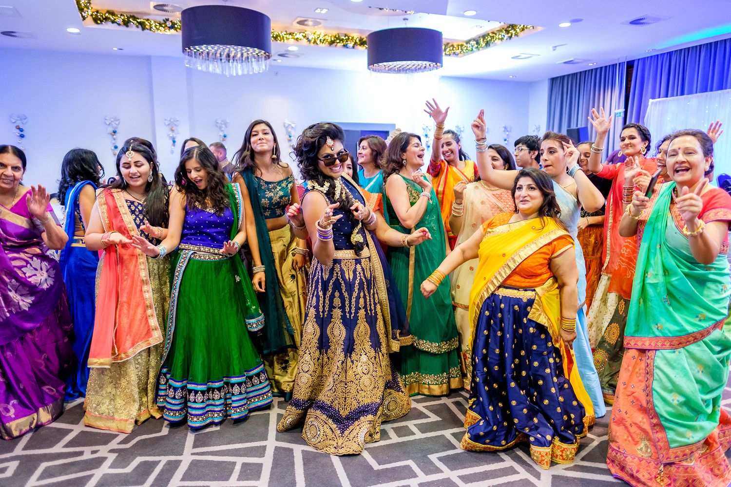 Wide shot of celebration showing dancers in colorful traditional attire performing in a decorated venue.