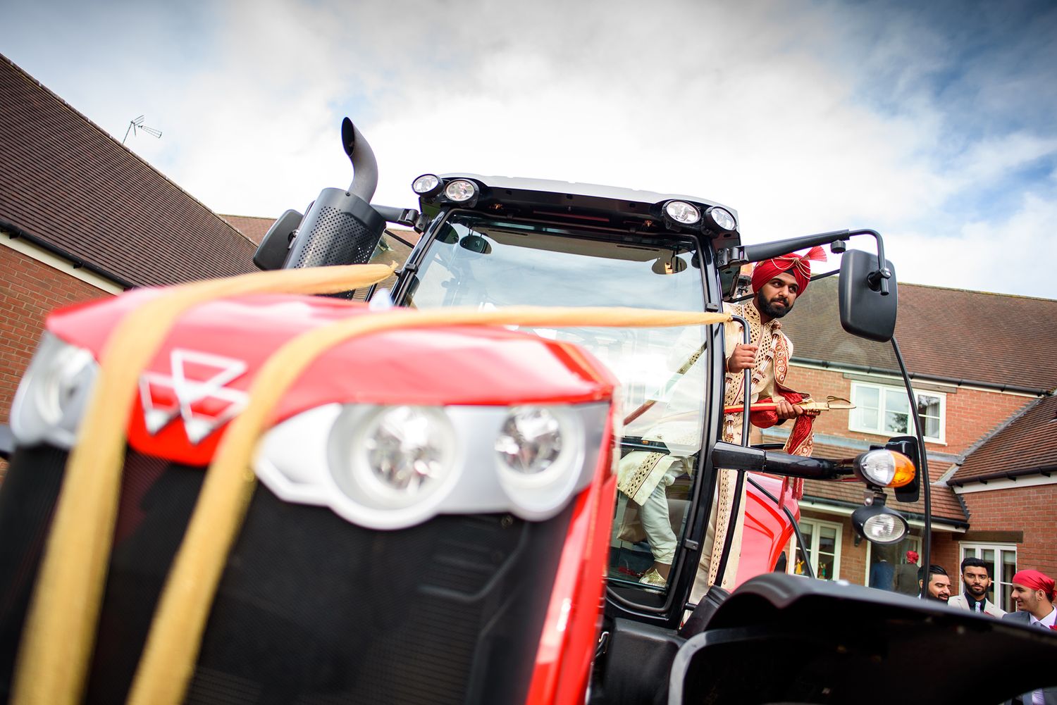 Red tractors lined up outside a Sikh temple against a cloudy sky.