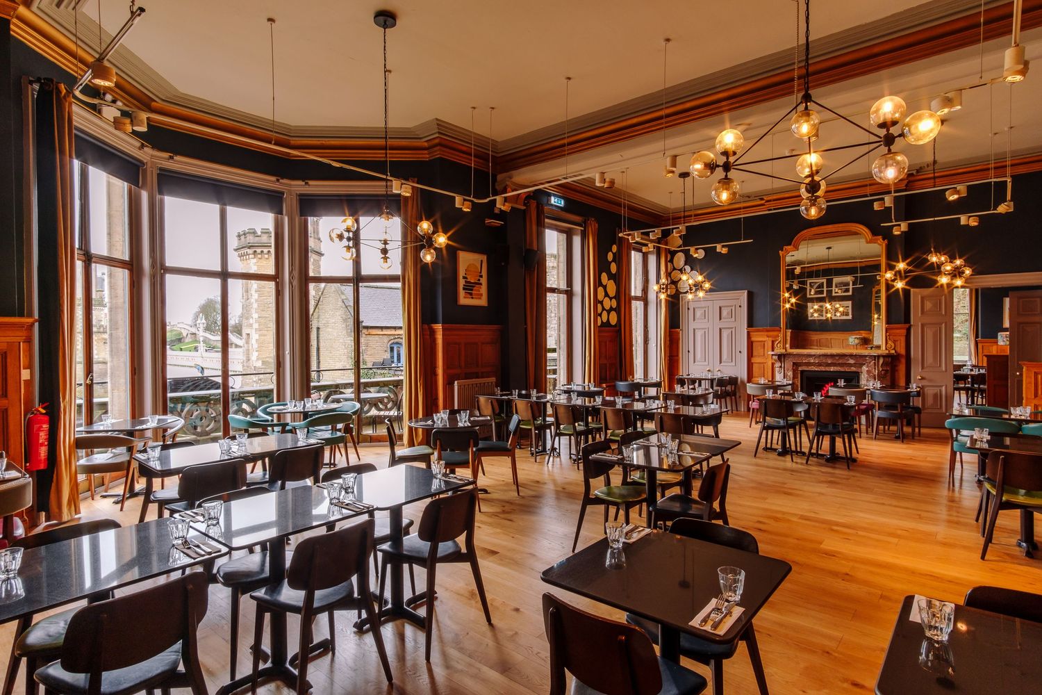 Spacious restaurant dining room with large windows and modern pendant lighting.