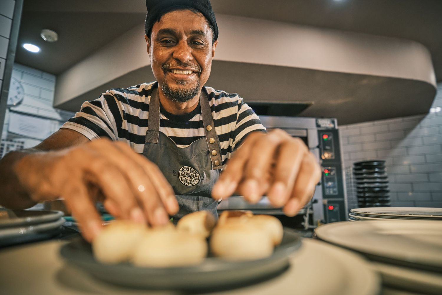 Restaurant worker in striped shirt preparing food in commercial kitchen.