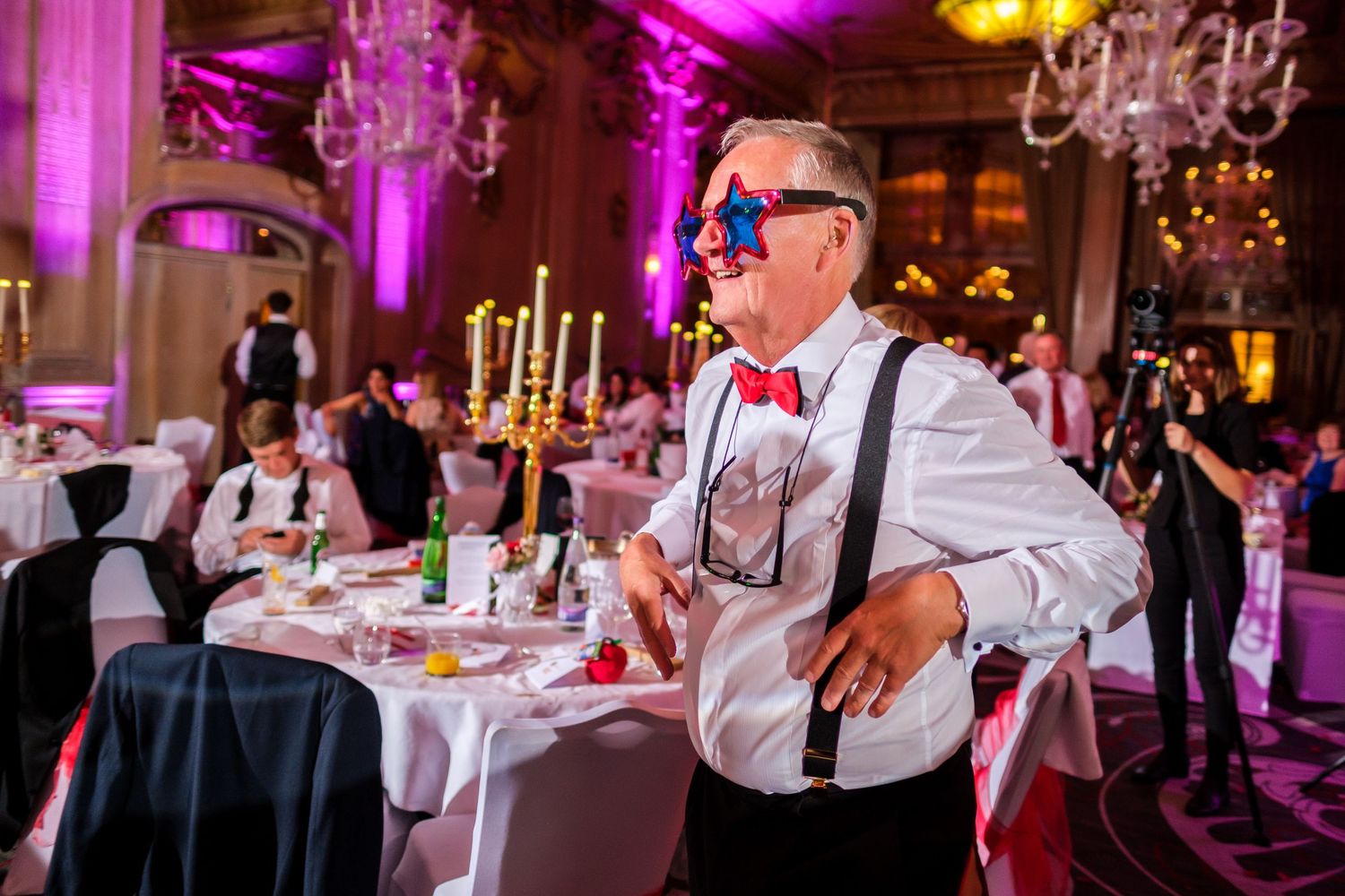 Wedding reception dance floor with purple ambient lighting and guests celebrating.