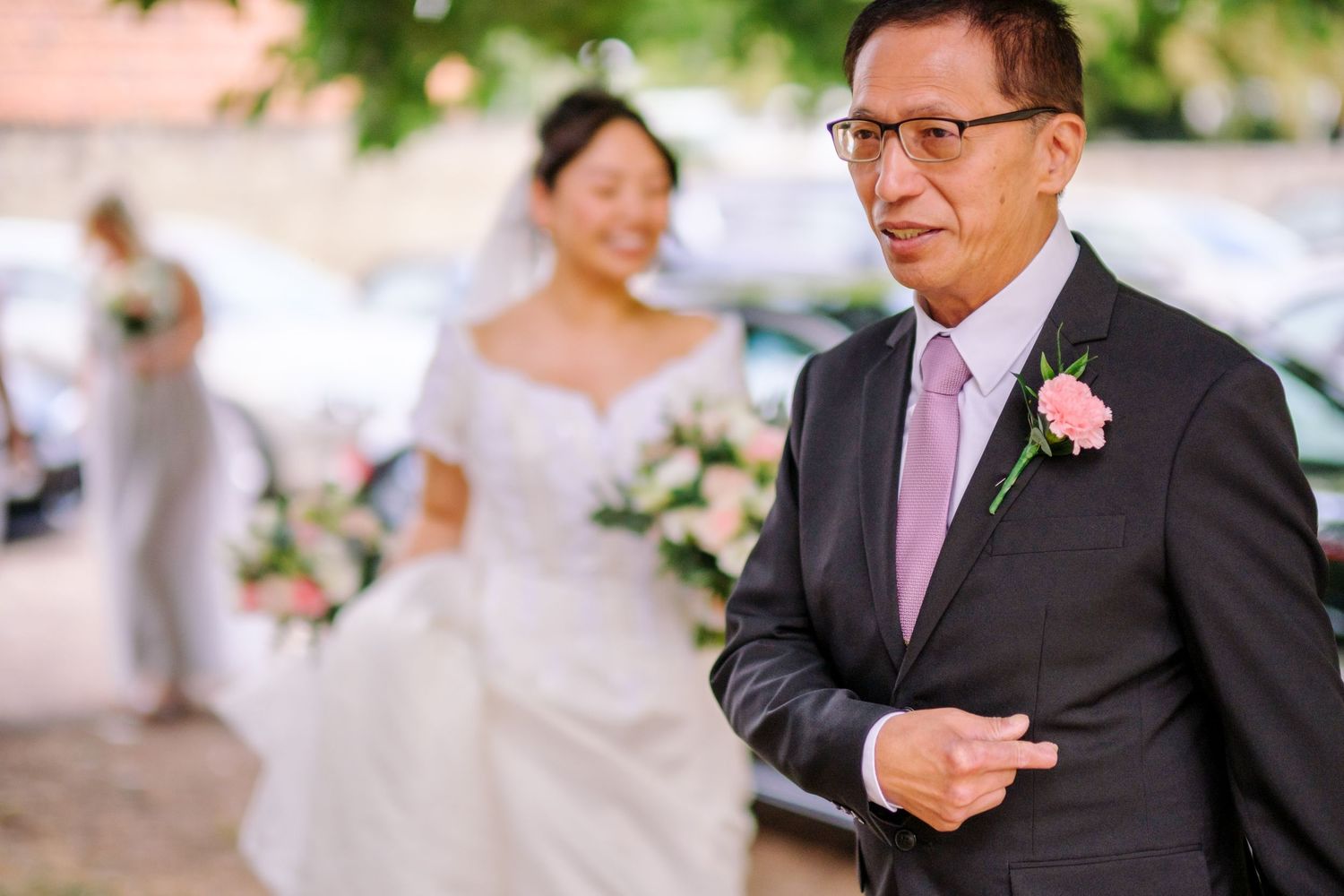 A wedding party celebrates outdoors in a garden setting with pink and white floral decorations.
