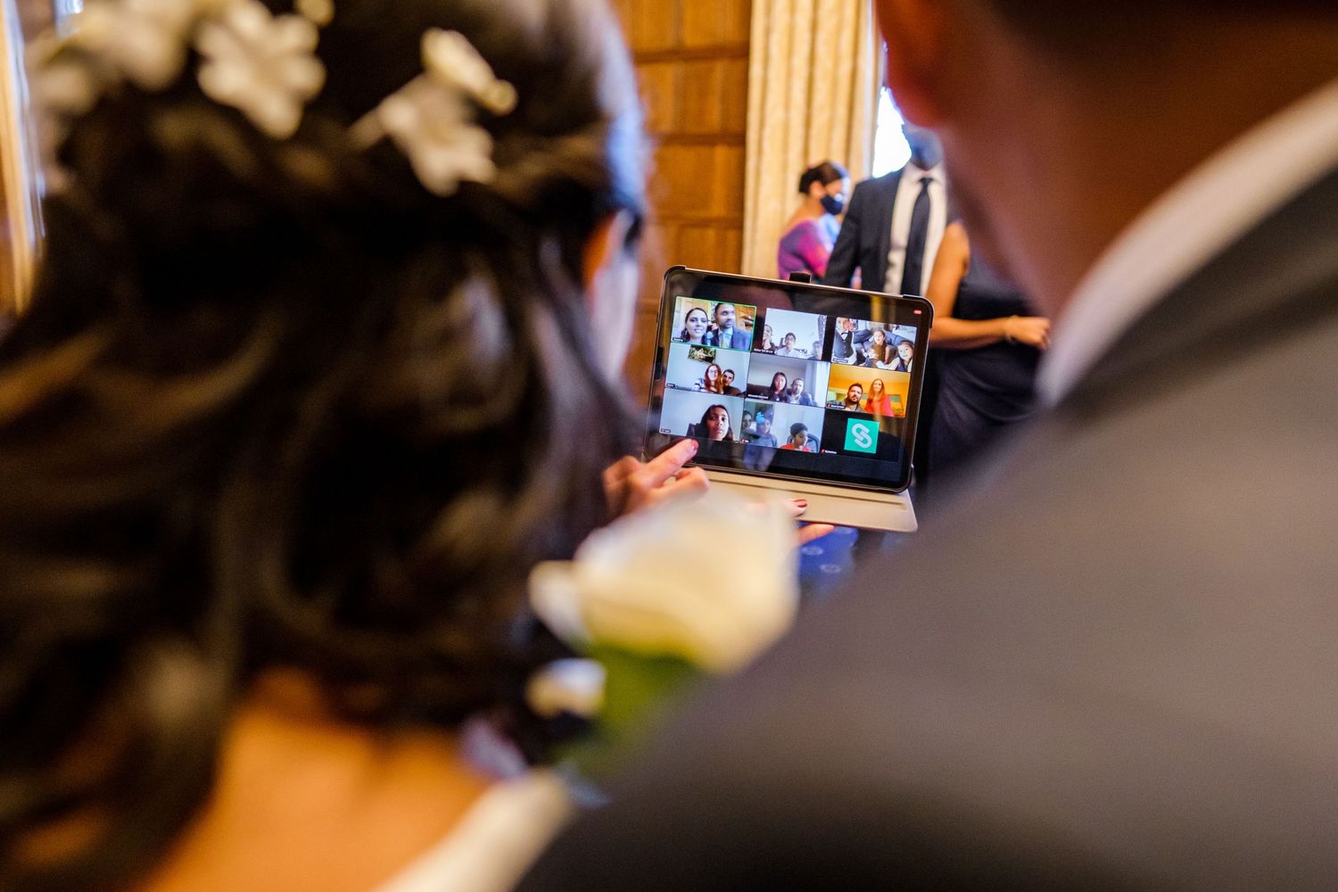 A person holds up a smartphone during a video call meeting in a warmly lit room.