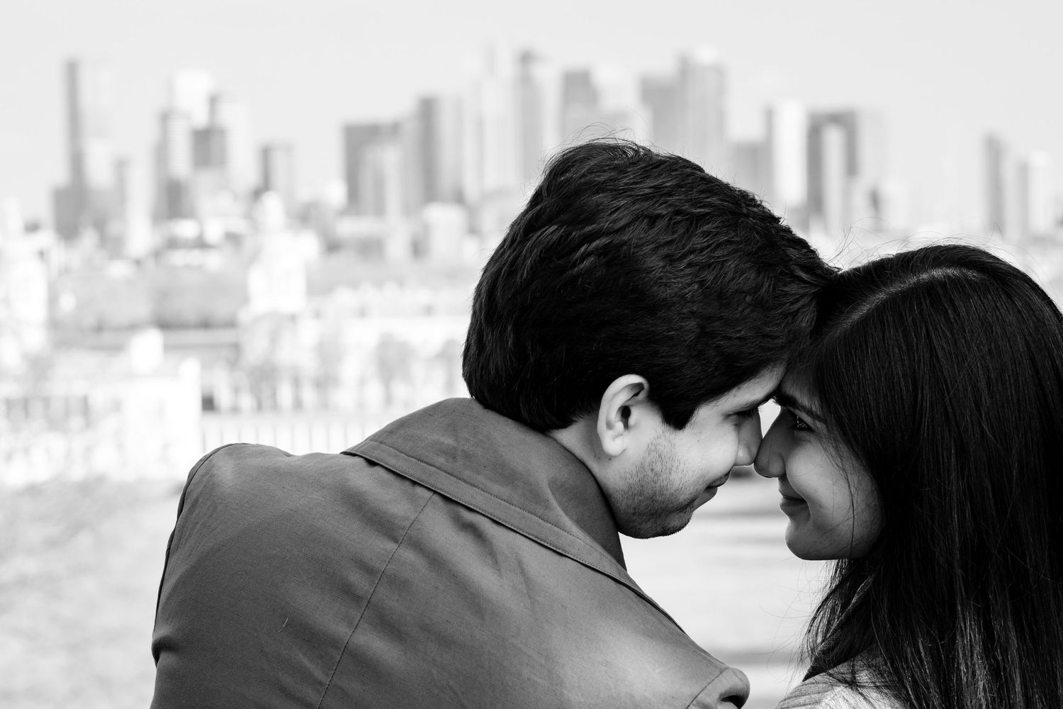 Romantic couple embraces under a cherry blossom tree with soft focus bokeh effect in the background.