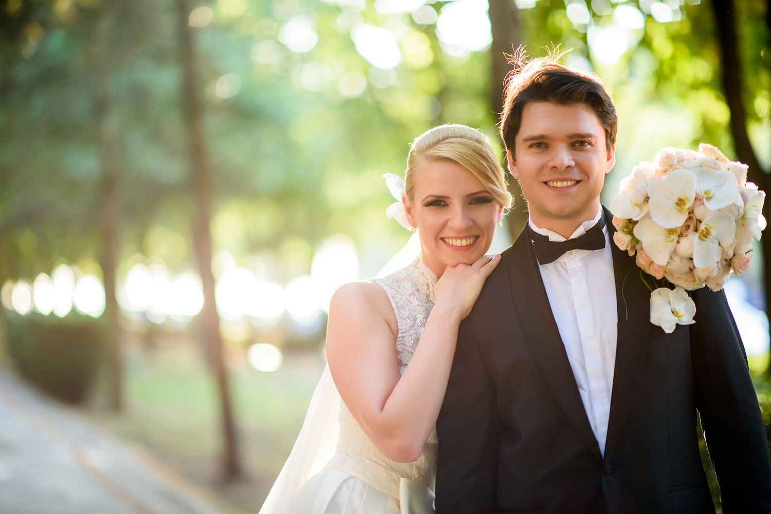 Sunlit outdoor wedding portrait with natural bokeh background.