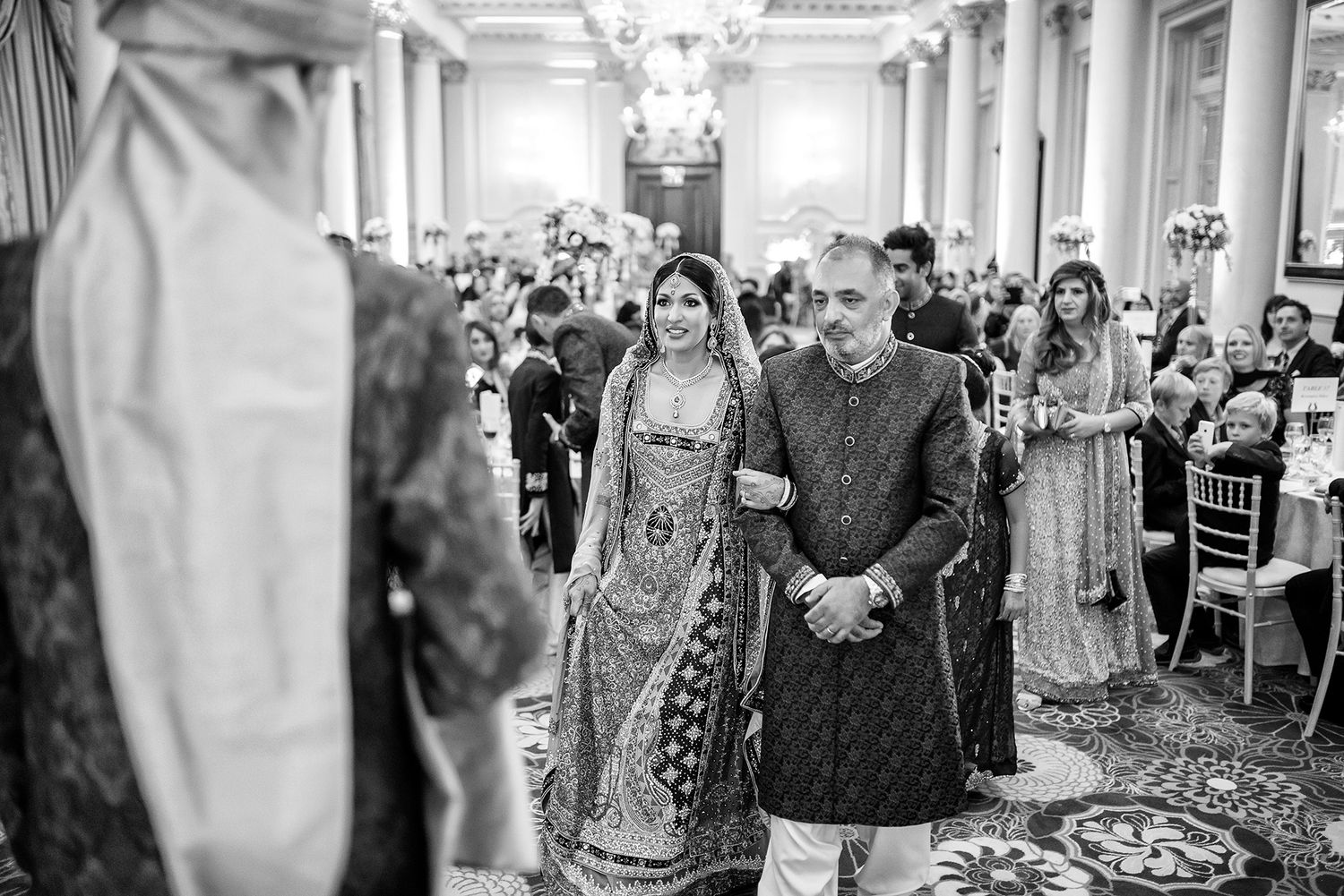 Elegant white pillared reception hall filled with wedding guests.