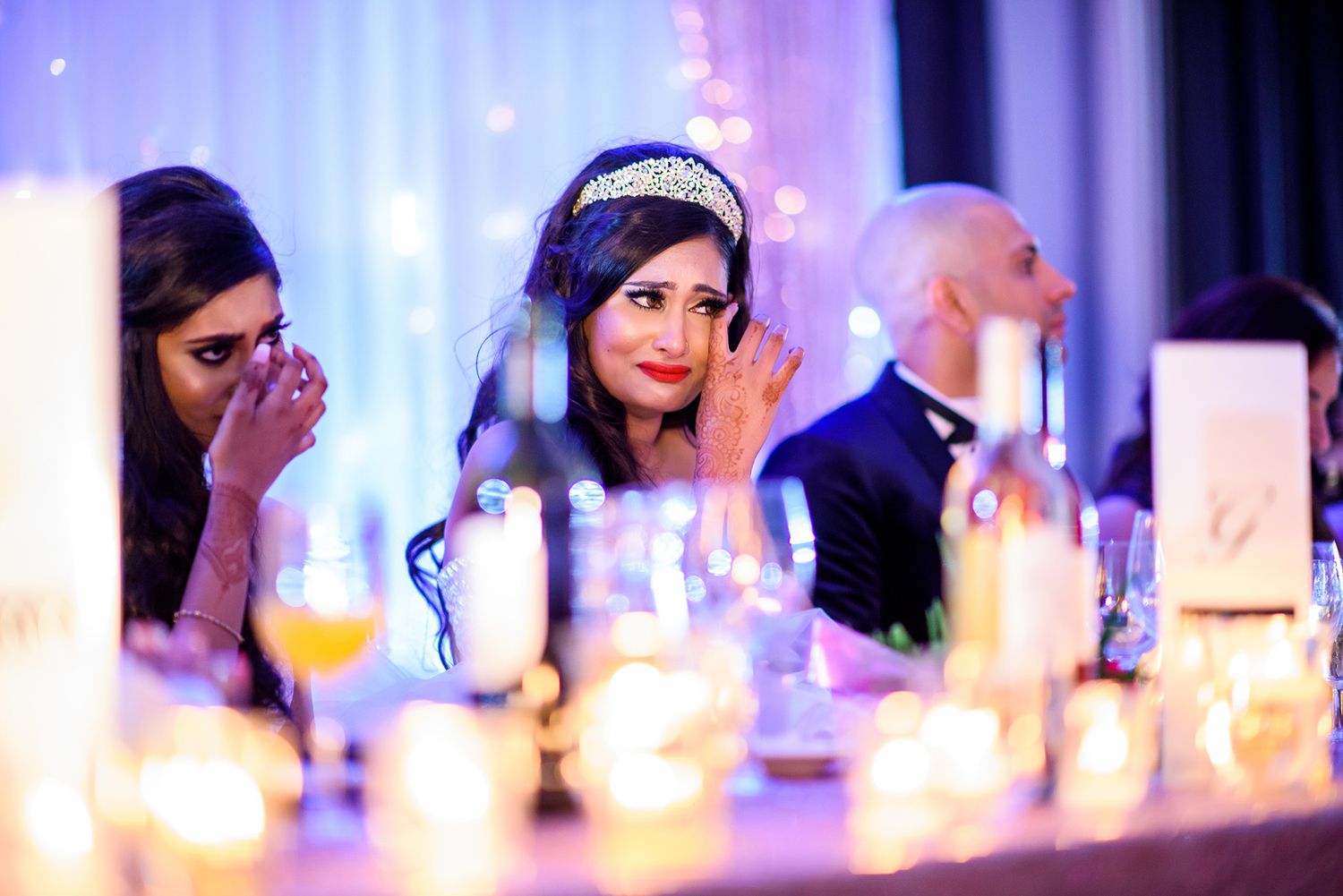 Candlelit wedding reception tables with elegant white and gold table settings.