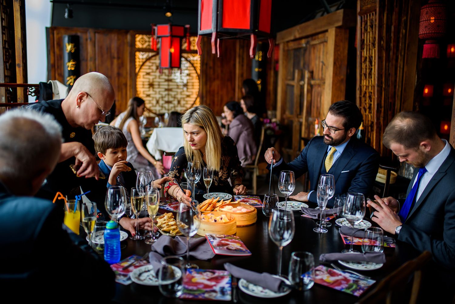 Warm lighting illuminates elegant dining room filled with guests at decorated tables.