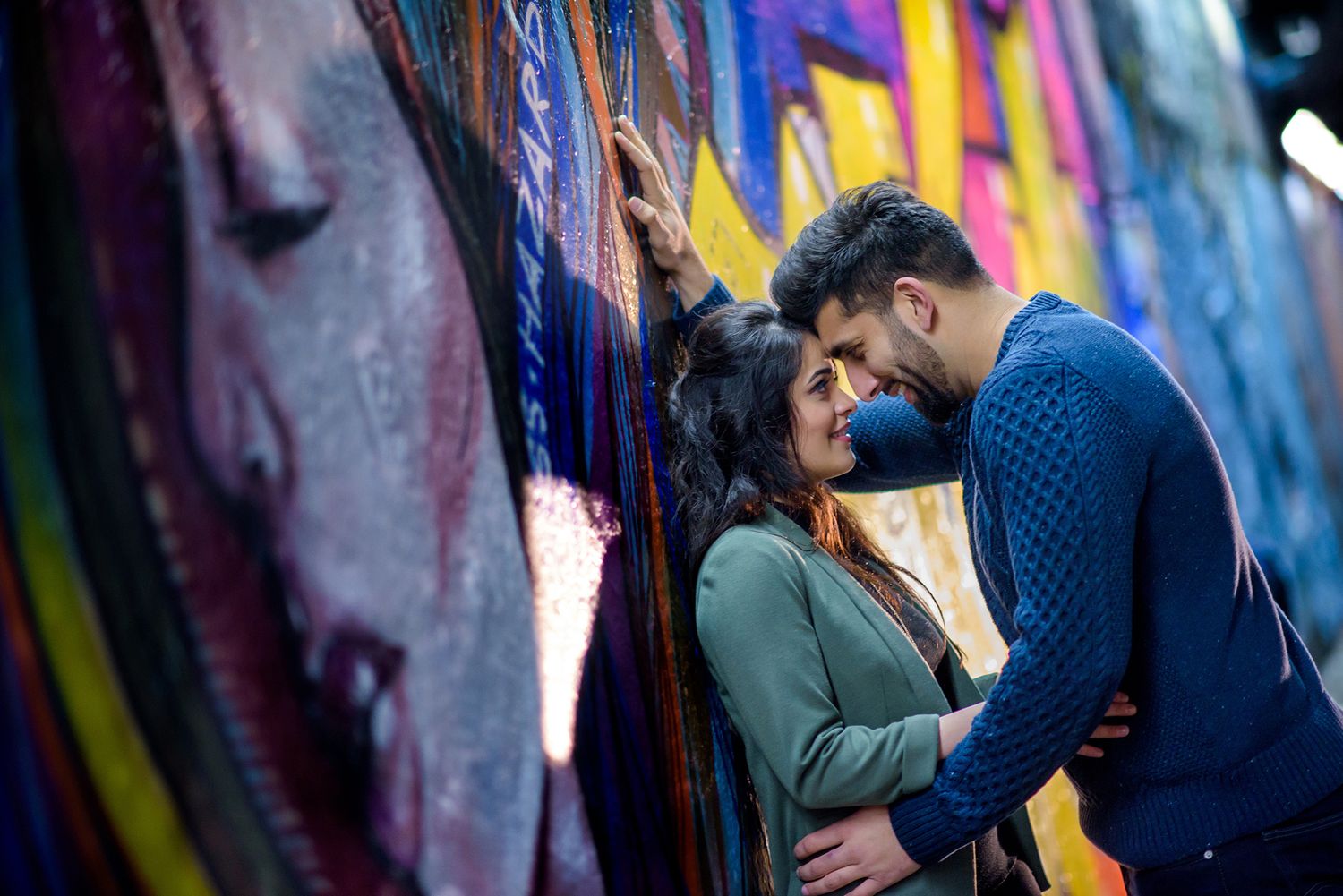 Romantic couples photoshoot against multicolored graffiti wall backdrop.