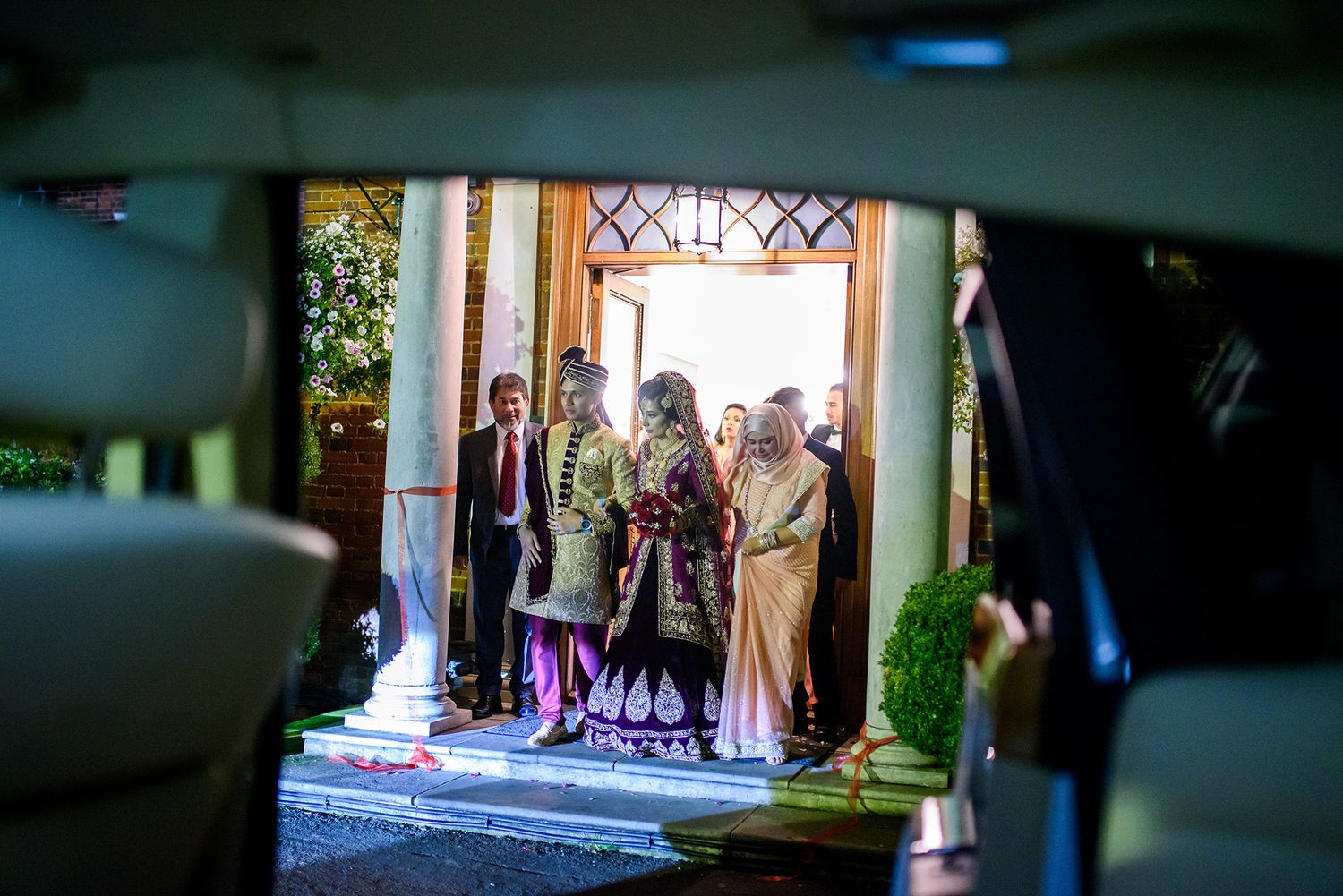 View through a car window of a traditional wedding entrance ceremony.