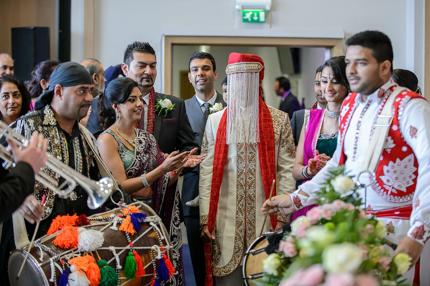 Guests mingle at a vibrant indoor wedding ceremony decorated with traditional Indian elements.