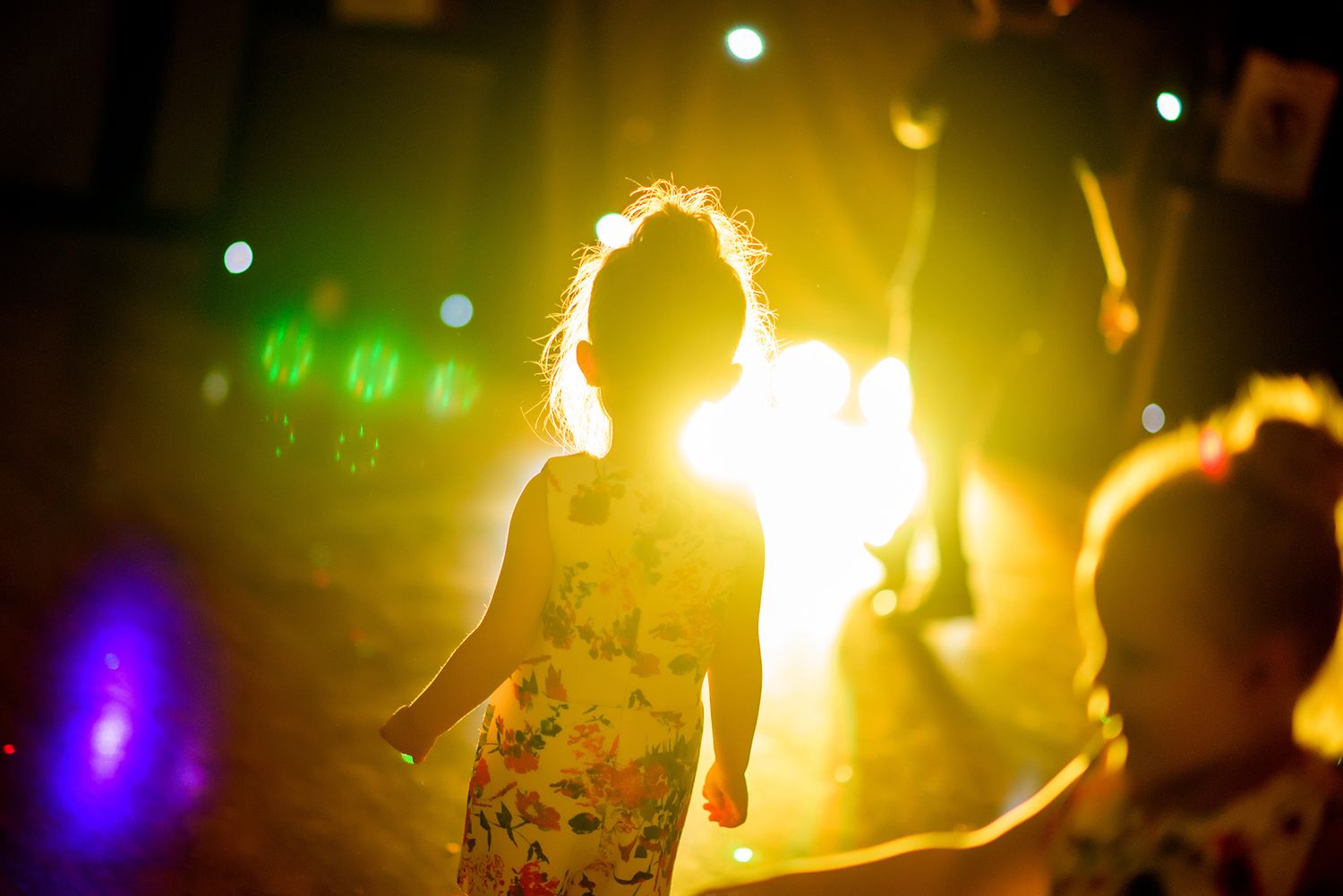 A silhouetted figure dances in warm lighting with colorful bokeh effects in the background.
