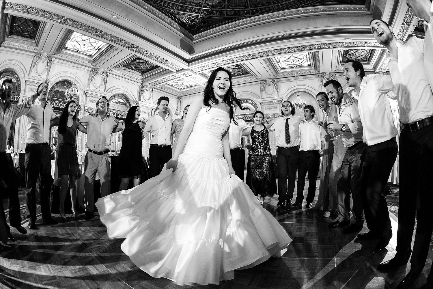 Panoramic view of a wedding celebration in an ornate ballroom with decorative ceiling.