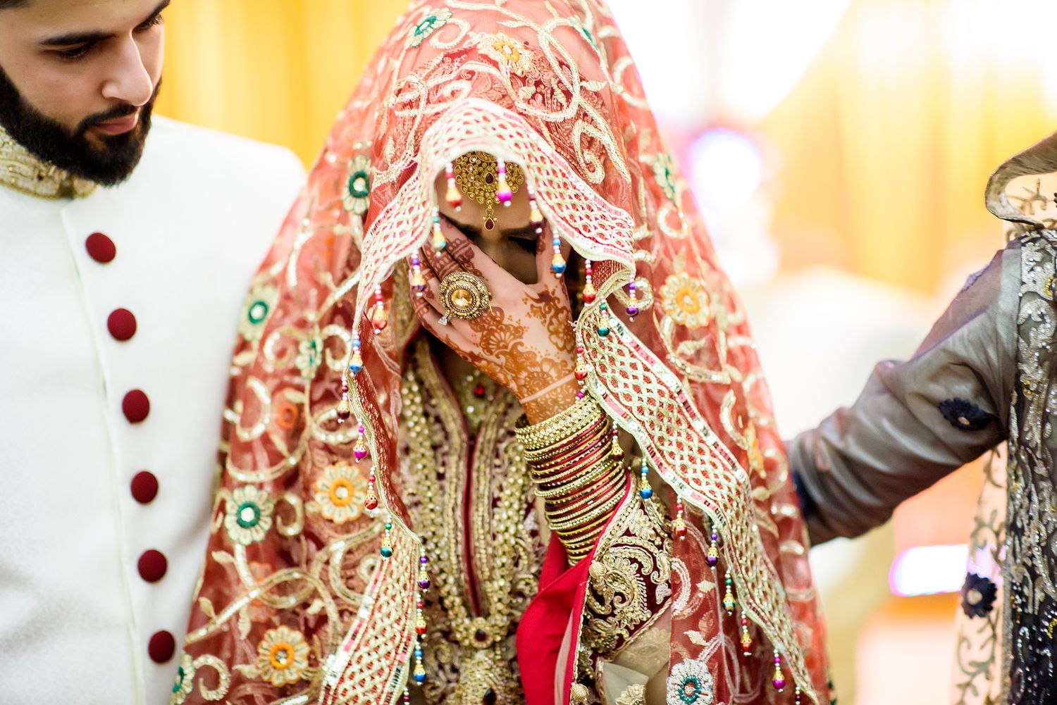 Traditional Indian wedding attire with intricate embroidered details in red and gold.