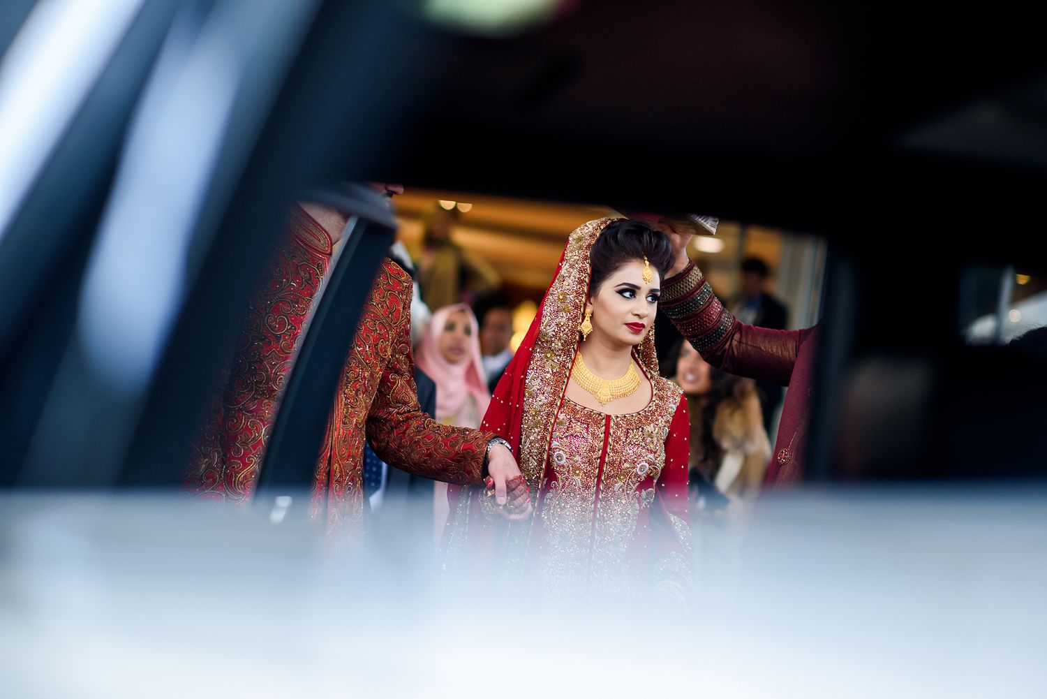 Close-up shot of traditional Indian bridal jewelry and ornate red and gold embroidered wedding attire.