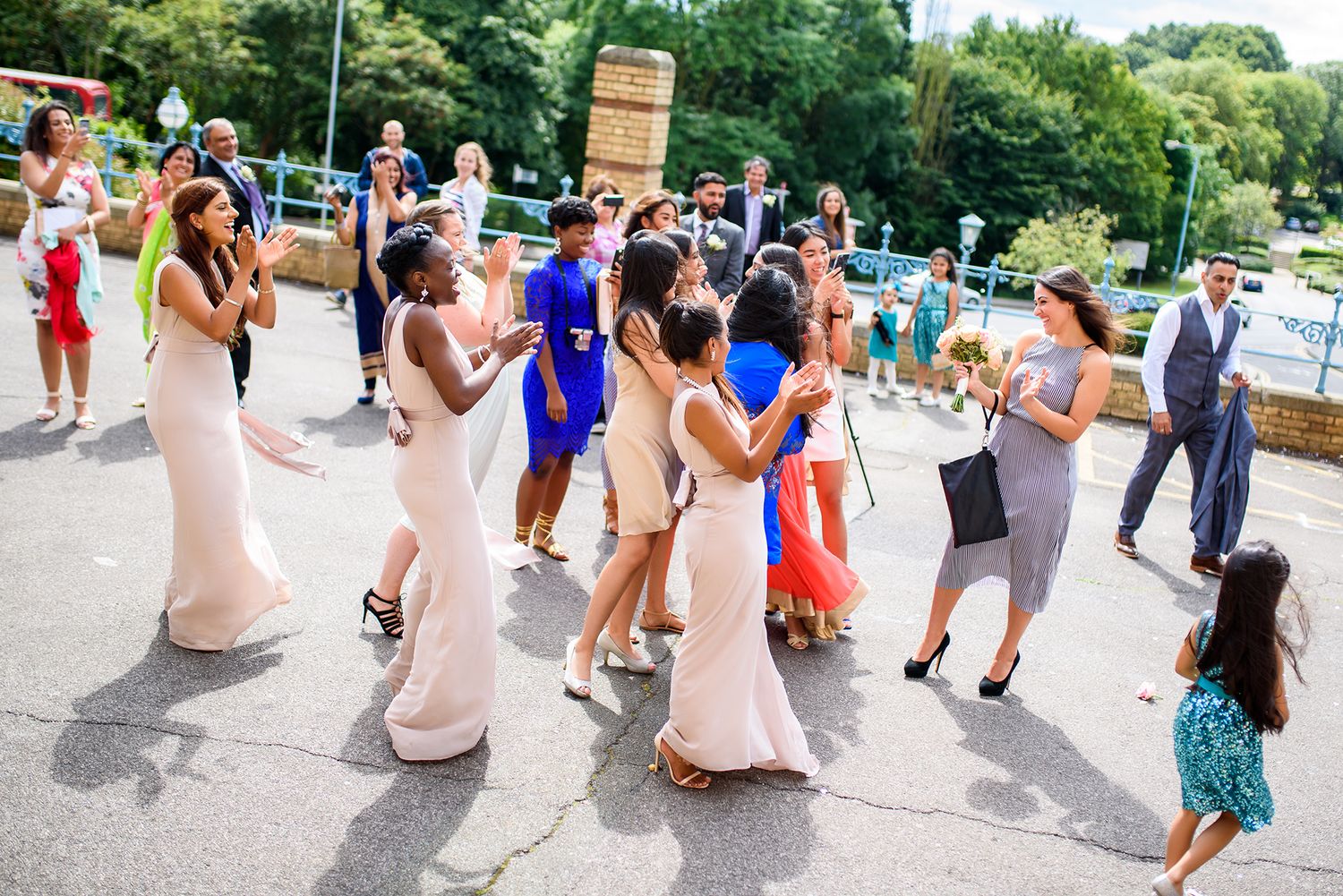 Wedding party and guests gather outside in summer for group photos.