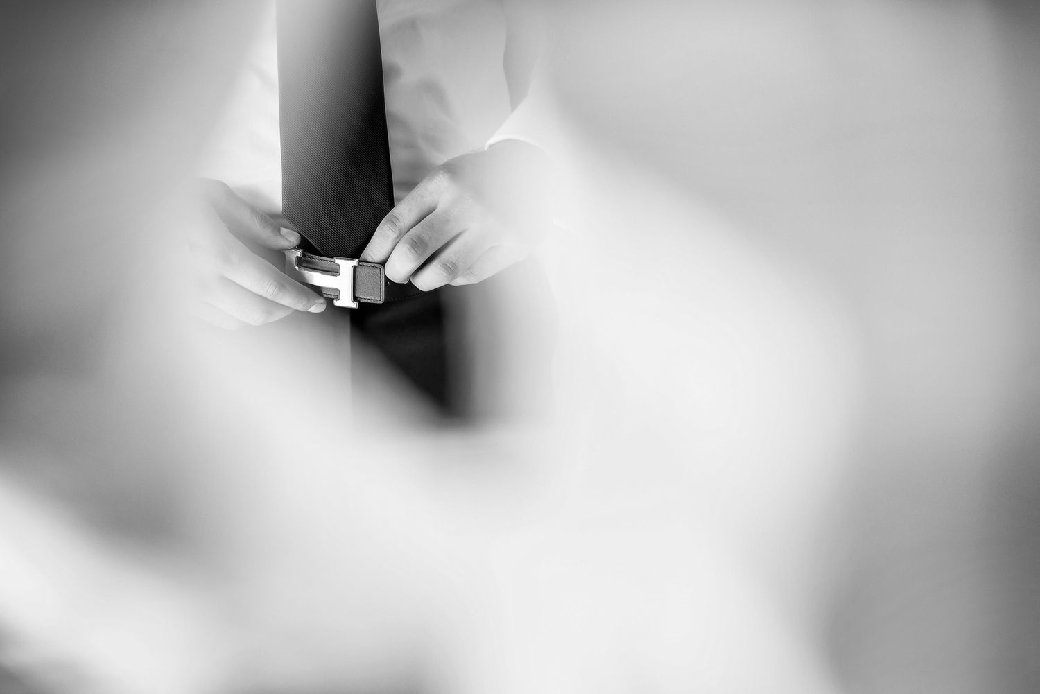 Black and white artistic close-up of hands exchanging rings during ceremony.