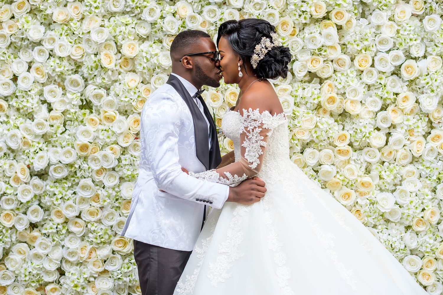 Wedding celebration against luxurious white flower wall backdrop.
