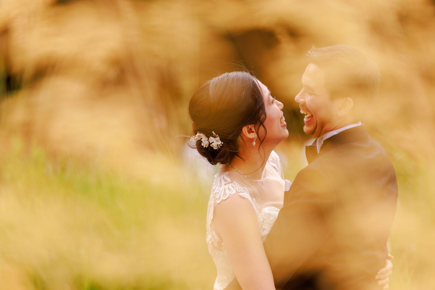 Artistic wedding photography through tall grass showing intimate moments between newlyweds.