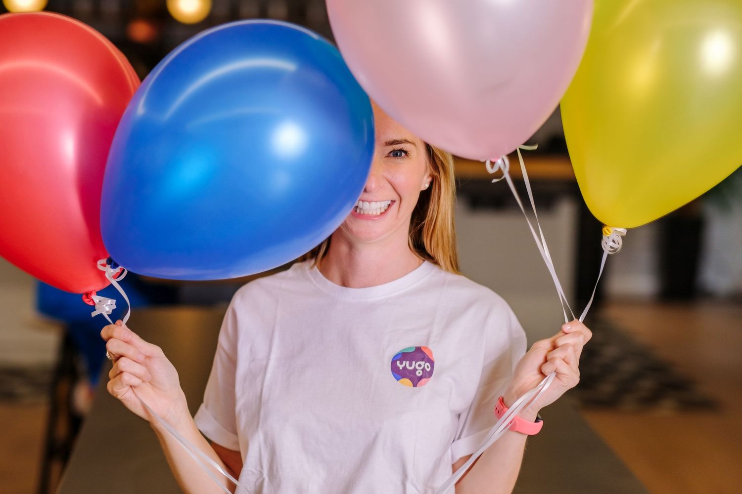 Colorful balloons being held by people in celebration against dark background.