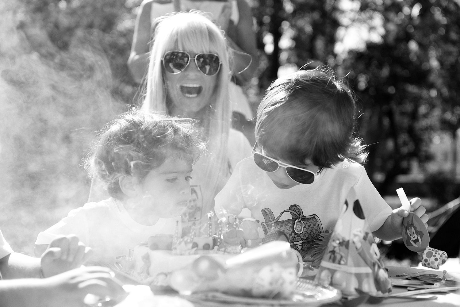Friends laughing together while lying on grass in black and white photography.